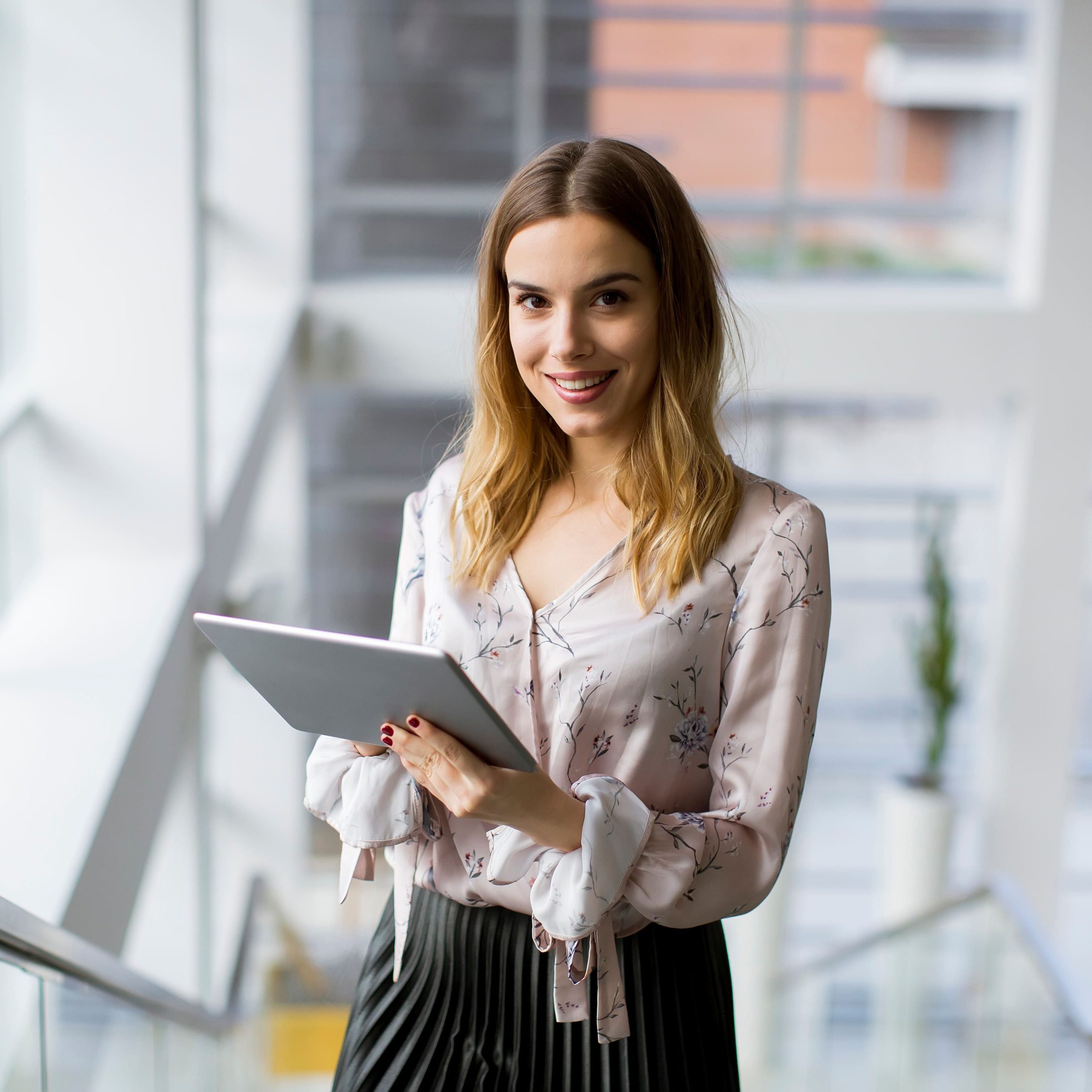 Attractive businesswoman using a digital tablet while standing on the stairs in the office